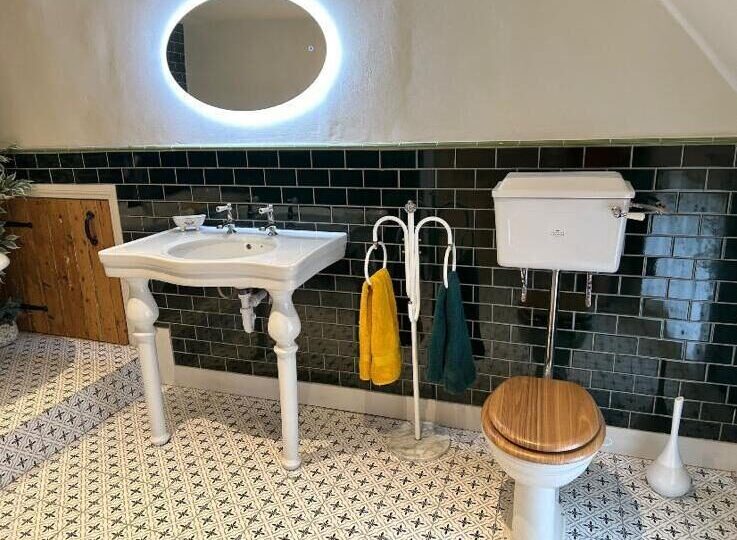 Traditional bathroom installation with console basin, dark green metro tiles and patterned encaustic floor by On-Tap Plumbing & Heating